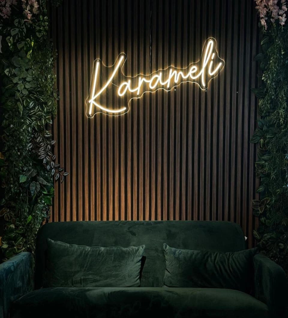 Le salon Karameli avec son enseigne lumineuse et son canapé vert